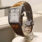Watch with brown leather strap and silver case on a white surface