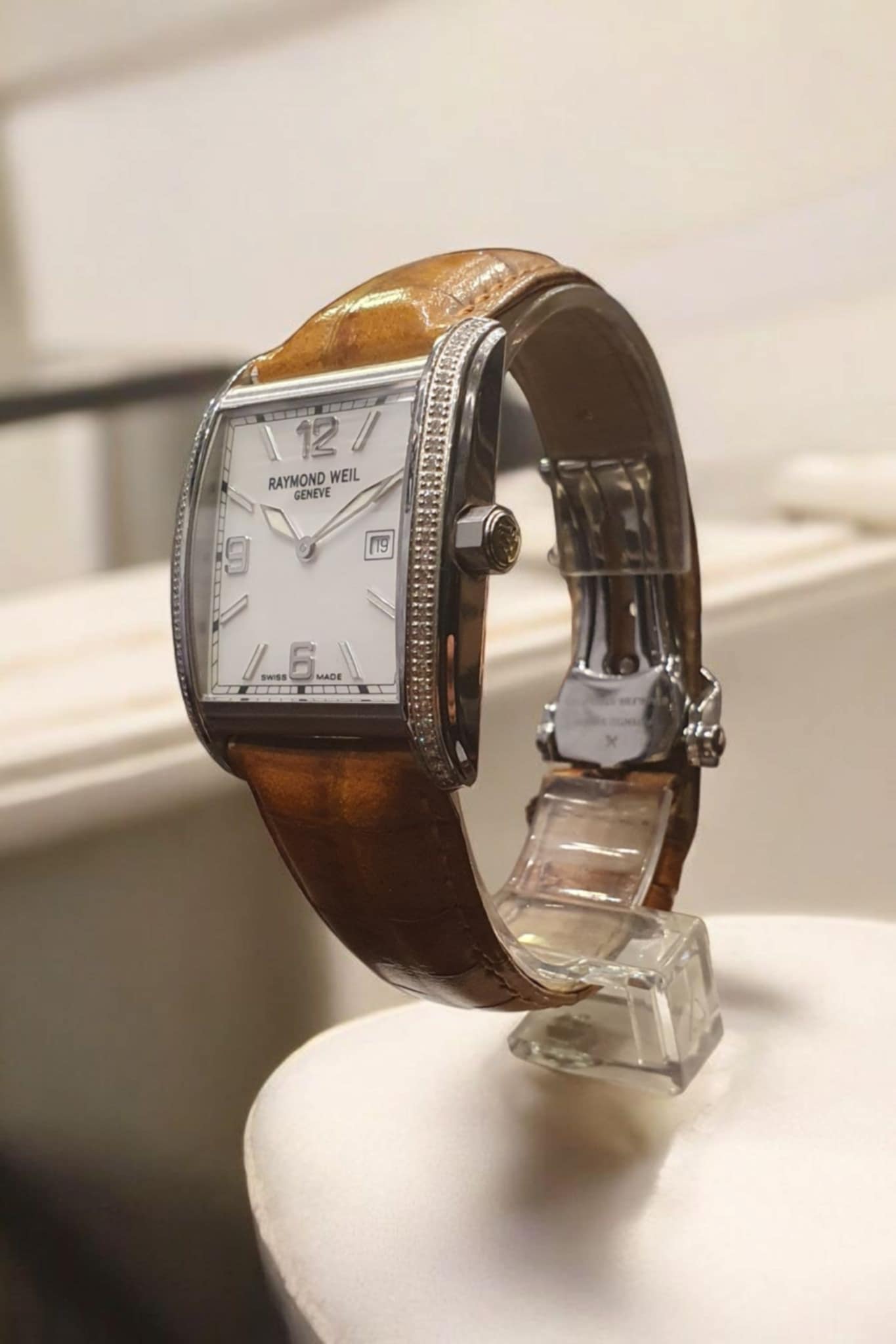 Watch with brown leather strap and silver case on a white surface